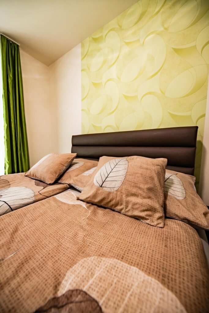 Zamárdi apartman szoba, zöld függöny és leveles ágytakaró.